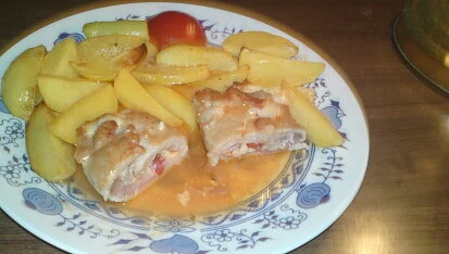 Dva kusy masa v omáčce s bramborami na talíři.