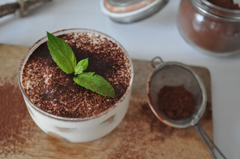 Hotový tiramisu v sklenici s čokoládou a mátou.