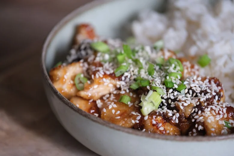 Teriyaki kuřecí maso s rýží v misce posypané sezamem.
