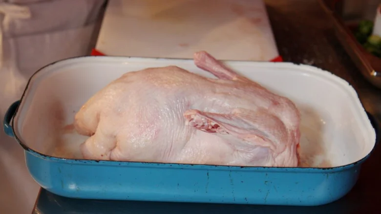 Surová kachna v modré pekáči připravená na vaření.