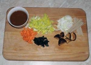 Ingredience pro přípravu polévky s misem na dřevěném prknu.