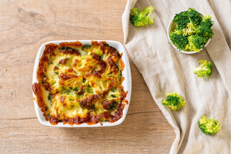 Pečený brokolicový gratin s čerstvými květy v bílé misce.