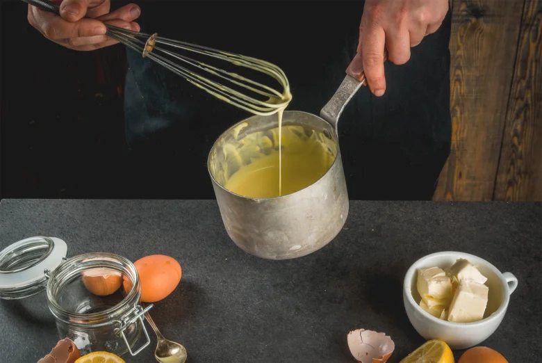 Kuchař míchá vejce v hrnci s ostatními ingrediencemi.