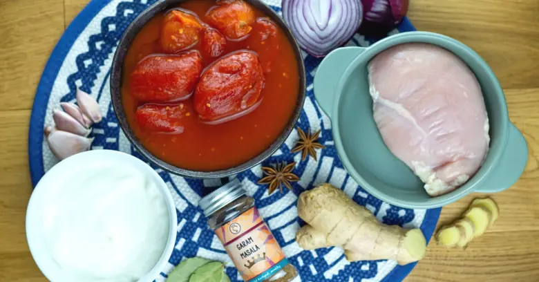 Suroviny pro kuřecí tikka masalu: kuře, rajčata, jogurt a koření.