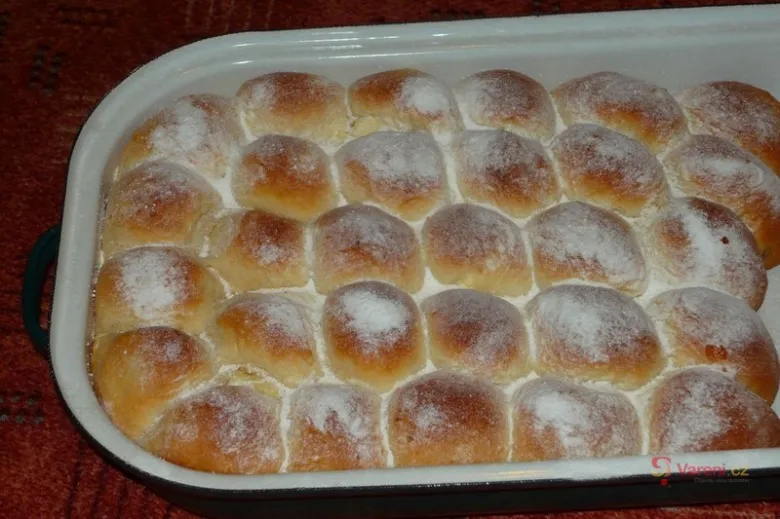 Běle zasypané buchty v bílé pekáči připravené k podání.