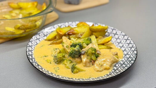 Zapečené brambory s brokolicí v krémové omáčce na talíři.