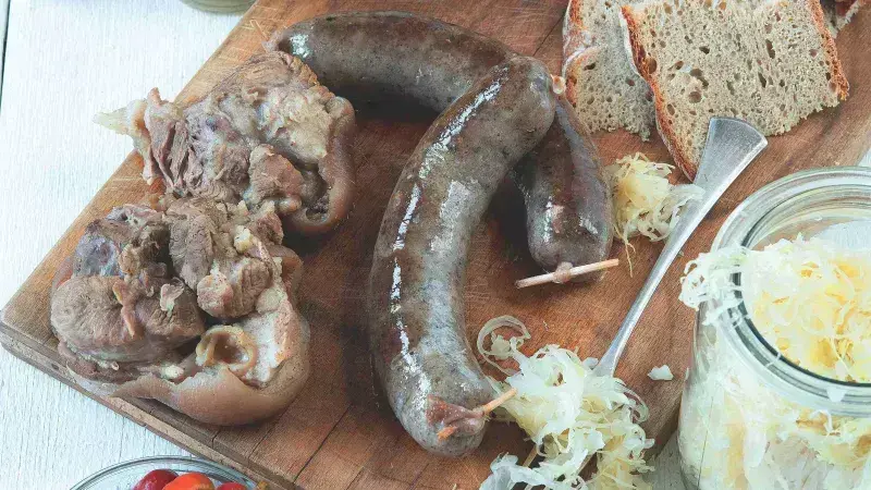 Připravené české klobásy a uzeniny na dřevěném prknu.