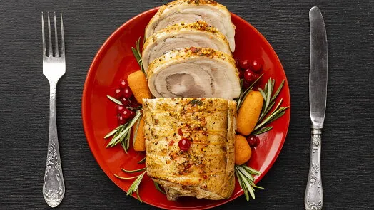 Načerveno vepřová roláda z pečeně s rozmarýnem na červeném talíři.