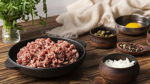 Surové mleté maso s ingrediencemi pro recept na biftečky.