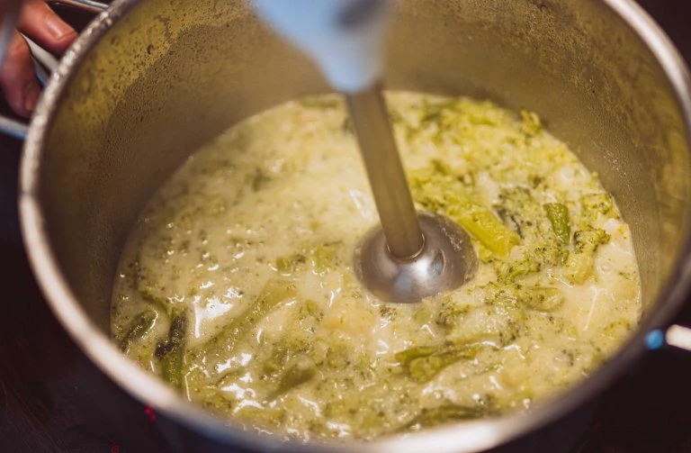 Mixování brokolice do krémové polévky pomocí ponorného mixéru.