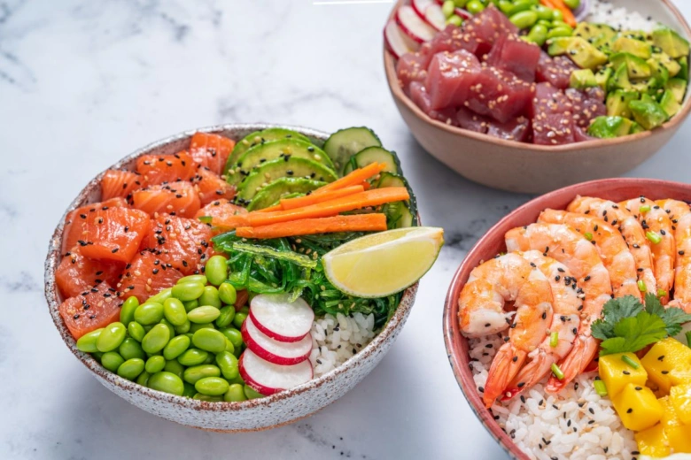 Tři barevné poke bowl s čerstvými ingrediencemi jako ryba, avokádo, edamame.