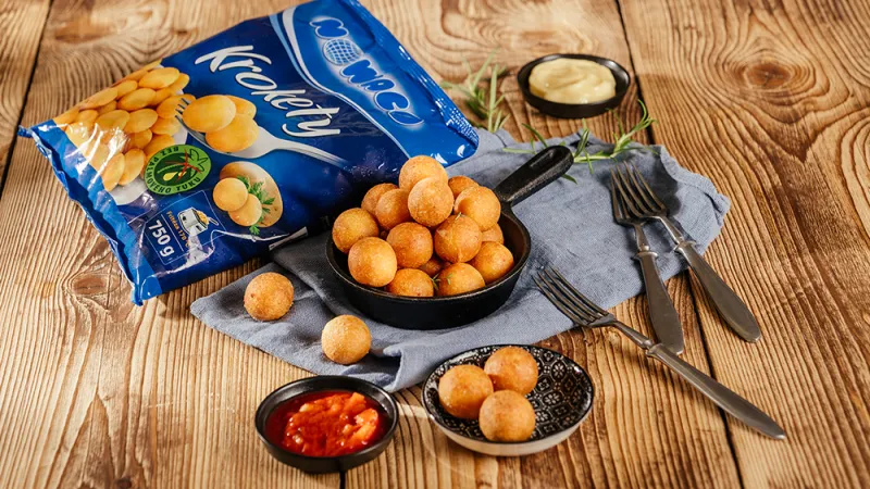 Mrazíkové bramborové krokety s omáčkami na dřevěném stole.