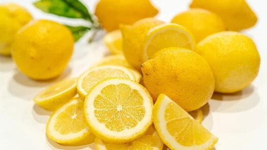 Žluté citrony celkové i nakrájené na bílém podkladu.