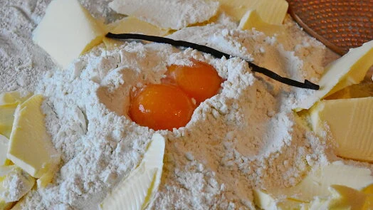Suroviny na pečení: mouka, vejce, máslo a vanilkový lus.
