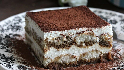 Kousek domácího dezertu tiramisú s vrstvami krému.