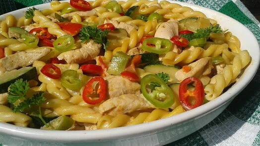 Pasta s kuřecím masem, paprikou a zeleninou v bílé misce.