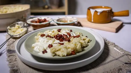 Brynzové halušky s křupavým vepřovým masem a bílým omáčkou.