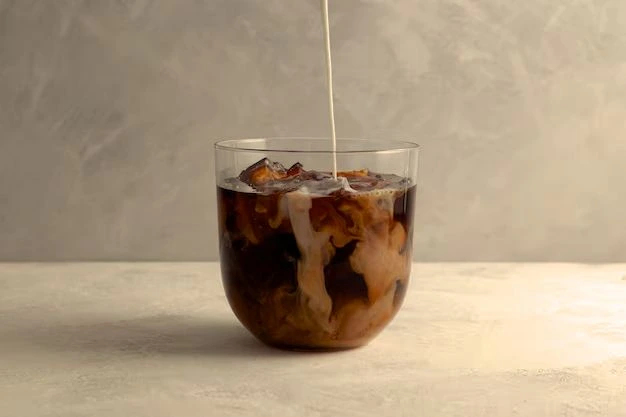 Mléko se nalévá do sklenice s ledem a kávou.