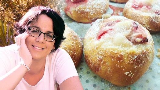 Žena se usmívá vedle svatebních koláčků posypaných cukrem.