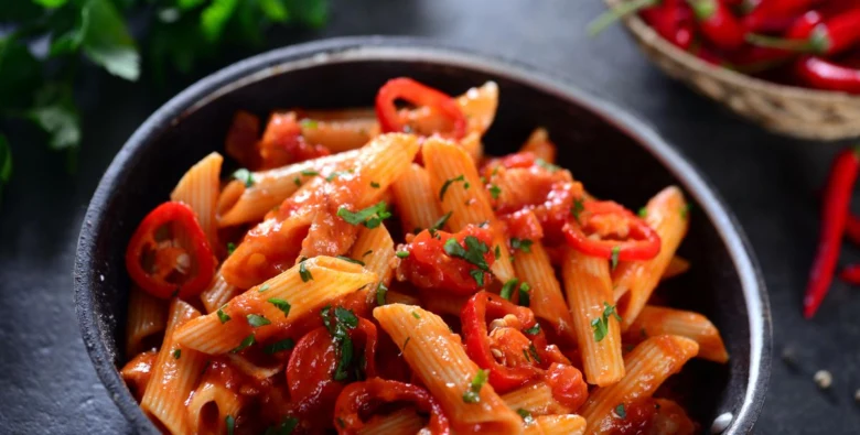 Penne s rajčatovou omáčkou, paprikami a bylinkami v misce.