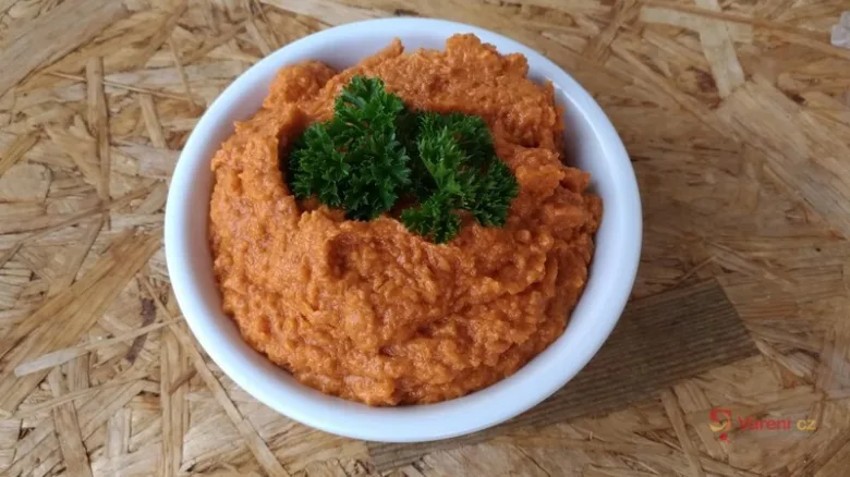 Bílá miska s oranžovou cuketou pomazánkou ozdobená petrželkou.