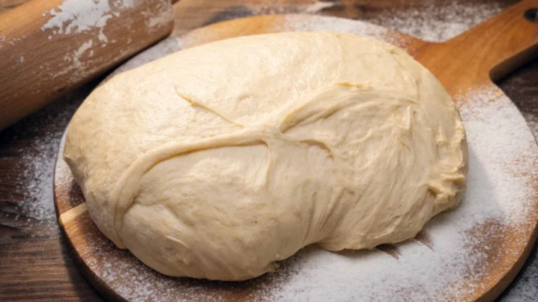 Kulová těsto na dřevěném prknu s moukou pro domácí trdelník.