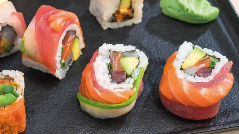 Různé druhy sushí na tmavém podnosu.