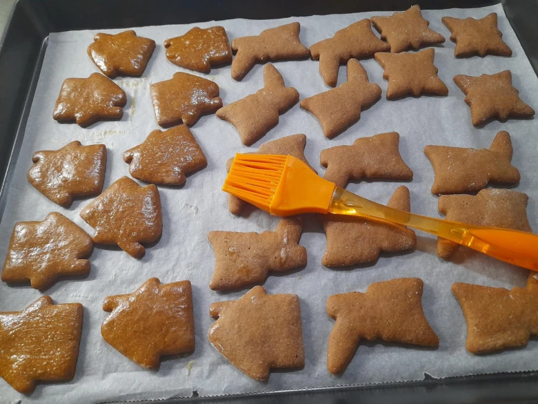 Vánoční perníčky tvarované jako zvířata s lesklým glazurou na plechu.