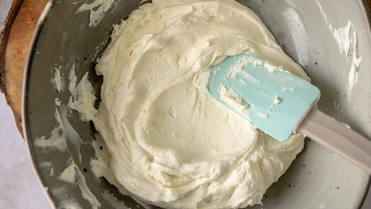 Bílá smetana s mascarpone se míchá v misce šlehačem.