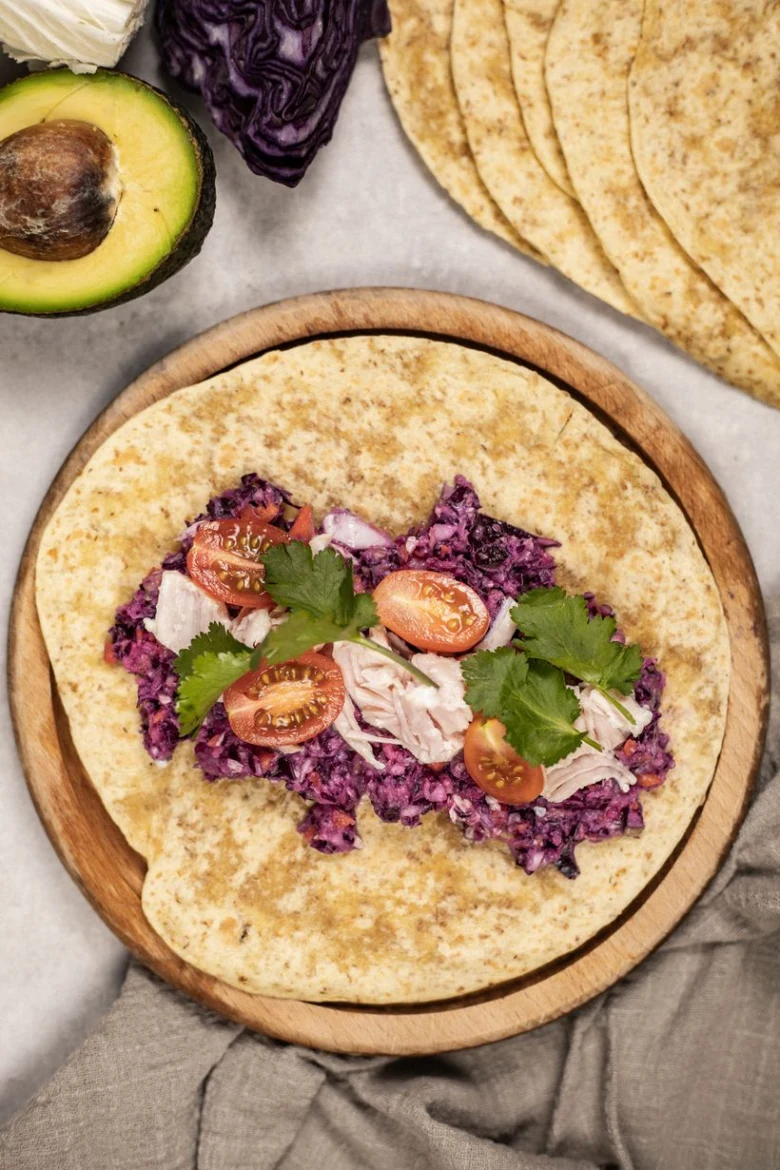 Tortilla s kuřecím masem, fialovou kapustou a rajčaty.
