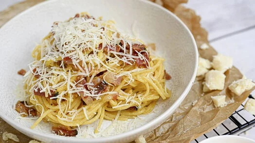 Miska se špagetami carbonara sýrem a kousky slaniny.