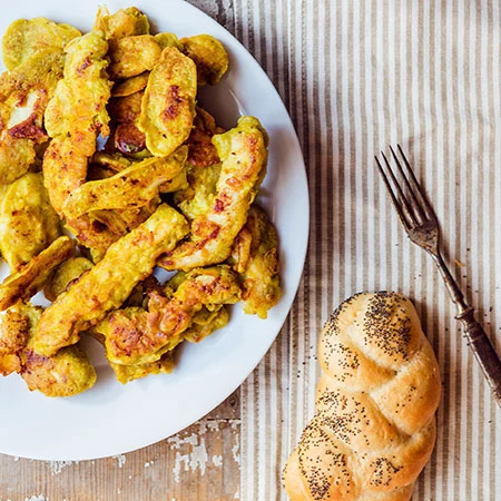 Breaded chicken pieces on plate with bread and fork