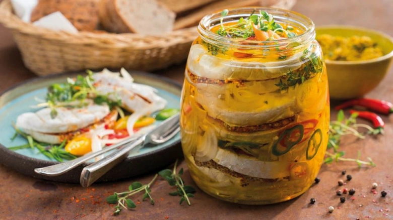 Sklenice utopců s vrstvenou rybou a zeleninou na talíři.