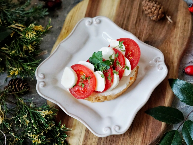 Domácí chlebík s rajčaty a mozzarellou na bílém talíři.