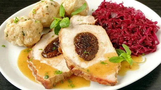 Uzené vepřové švejků s plněním, knedlíky a červenou kapustou.