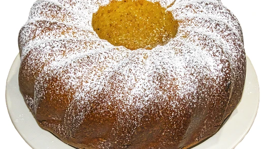 Bábovka s vaječným likérem posypaná moučkou na talíři.