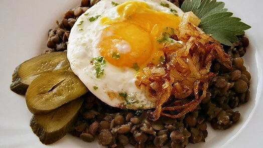 Hot lentil soup with fried egg, pickles and herbs.