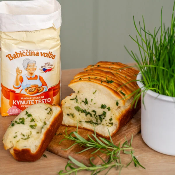 Kousek chlebových knedlíků s bylinkami vedle balení mouky.