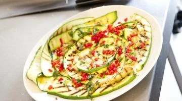 Grilované okurky s chilli a bylinkami na bílém talíři.