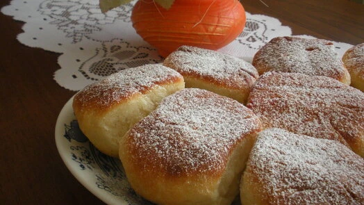 Zlatohnědé buchty posypané moučkovým cukrem na talíři.