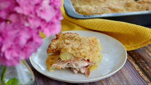 Porce zapečeného masa s bramborami na talíři.