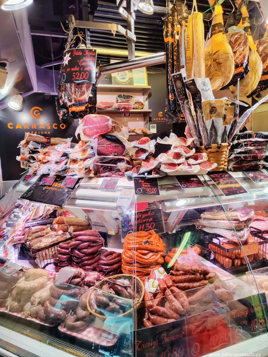 Výběr španělských uzených mas, salámů a jamon v tržnici.