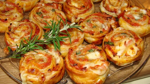 Pečené pizzové šneky s rozmarýnem na skleněném talíři.