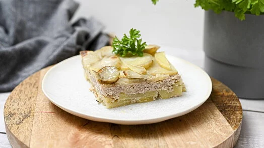 Kousek zapečených brambor s masem na talíři.