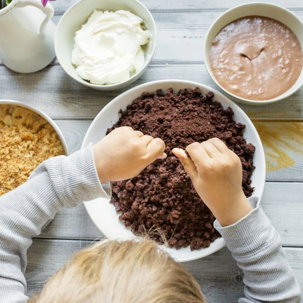 Dětské ruce míchají čokoládové krutiny pro výrobu cake popů.