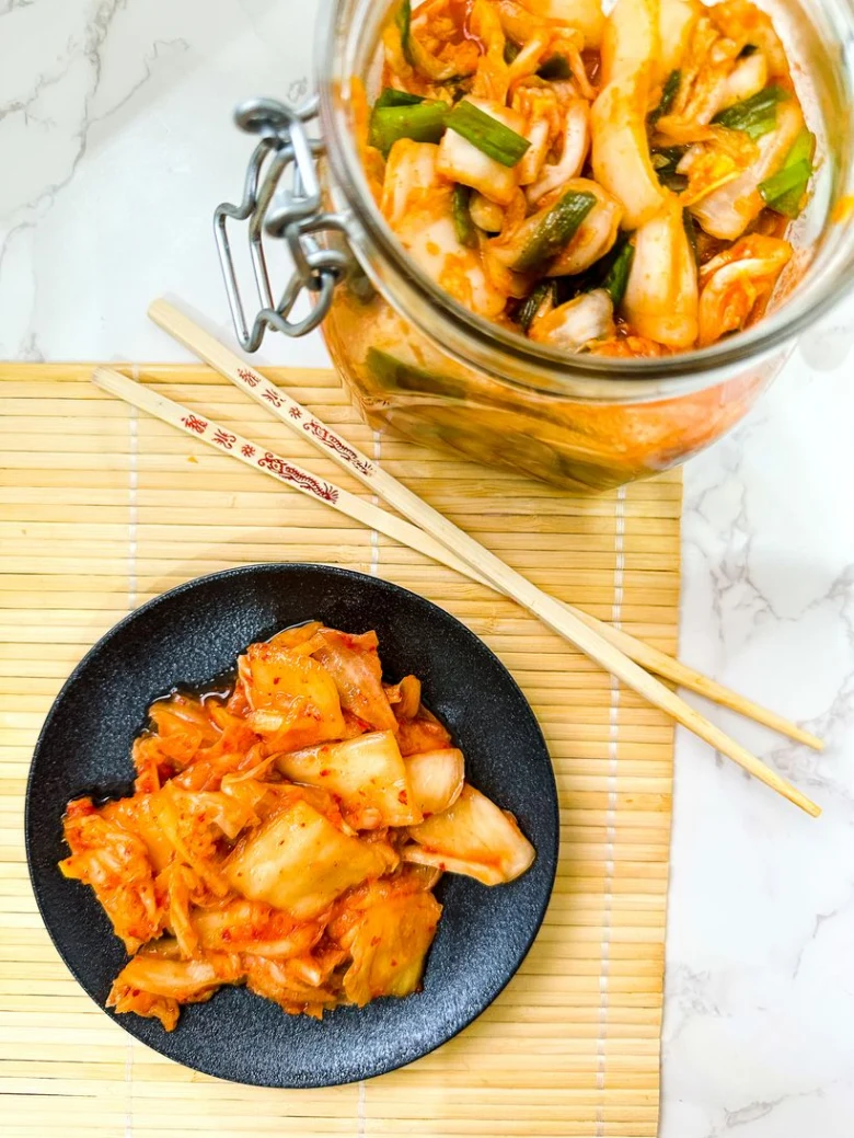 Fermentovaná korejská kapusta v sklenici na bambusové podložce.
