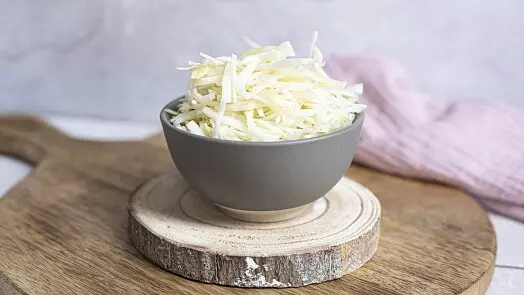 Mísa se nakrájenou bílou kapustou na dřevěném podkladu.