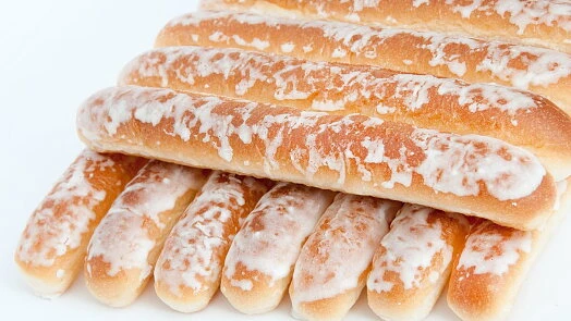 Zlatohnedé glazované preclíky na bílém pozadí.