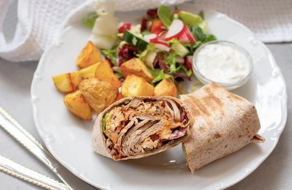 Filled tortilla wrap with salad and dip