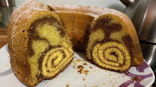 Kus mramorové buchtu posypaný cukrem na talíři.